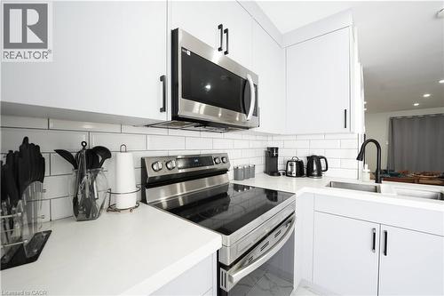 White shaker-style cabinetry with matte black hardware, stainless steel appliances, subway tile backsplash, and a black gooseneck faucet - 136 Jansen Avenue, Kitchener, ON - Indoor Photo Showing Kitchen With Upgraded Kitchen