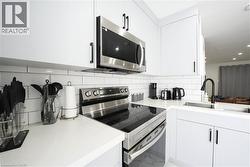 White shaker-style cabinetry with matte black hardware, stainless steel appliances, subway tile backsplash, and a black gooseneck faucet - 