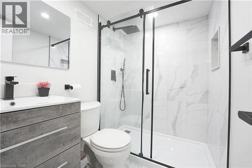 Bathroom featuring a frameless glass shower enclosure with matte black hardware, white marble-look tile, a built-in shower niche, and a vanity with a rectangular sink and matte black faucet - 136 Jansen Avenue, Kitchener, ON - Indoor Photo Showing Bathroom