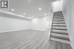 Spacious finished room featuring light wood-finish flooring, white painted walls, and recessed lighting - 