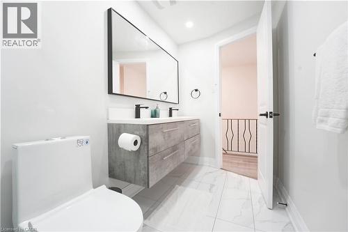Modern bathroom featuring a floating double vanity with a light gray wood-grain finish, dual vessel sinks, and matte black fixtures - 136 Jansen Avenue, Kitchener, ON - Indoor Photo Showing Bathroom