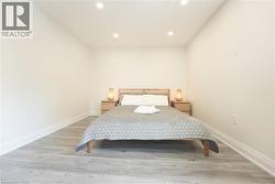 Bedroom featuring recessed lighting, light wood-finish flooring, white baseboards, and neutral wall paint - 