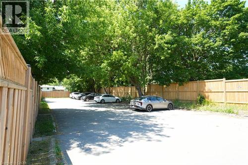 Paved parking area featuring mature trees, wood privacy fencing, and ample space for multiple vehicles - 136 Jansen Avenue, Kitchener, ON - Outdoor