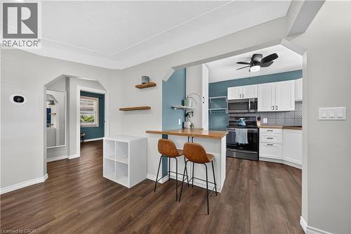 Open-concept layout featuring wood-finish flooring, arched doorways, and a kitchen with white cabinetry, a patterned tile backsplash, and dark appliances - 621 Tate Avenue, Hamilton, ON - Indoor Photo Showing Kitchen