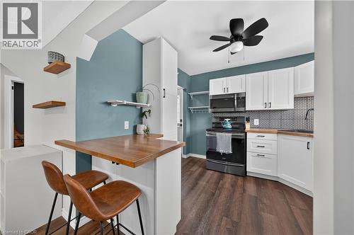 Contemporary kitchen featuring white cabinetry, wood-finish countertops, and a black appliance suite including a range and microwave - 621 Tate Avenue, Hamilton, ON - Indoor Photo Showing Other Room