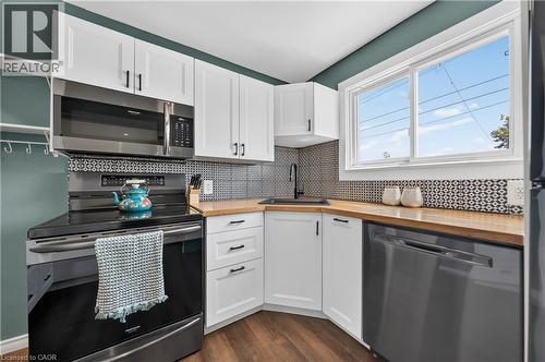 Modern kitchen featuring white shaker cabinetry, wood-finish countertops, and a patterned tile backsplash - 621 Tate Avenue, Hamilton, ON - Indoor Photo Showing Kitchen