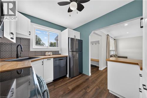 Kitchen featuring white cabinetry with matte black hardware, wood-finish countertops, and a patterned tile backsplash - 621 Tate Avenue, Hamilton, ON - Indoor Photo Showing Kitchen