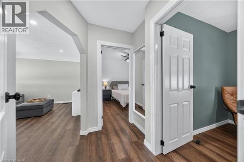 Hallway featuring wood-finish flooring, white baseboards, and white paneled doors with black hardware - 621 Tate Avenue, Hamilton, ON - Indoor Photo Showing Other Room