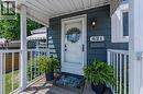 Front entry featuring a covered porch, white railing, blue horizontal siding, and an exterior wall lantern - 621 Tate Avenue, Hamilton, ON  - Outdoor With Deck Patio Veranda 