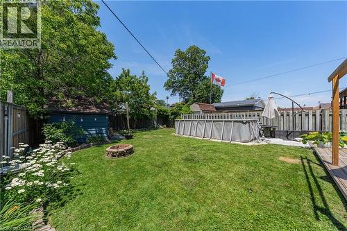 Expansive backyard featuring a manicured lawn, an above-ground pool, a stone fire pit, a wooden deck, and a detached shed - 621 Tate Avenue, Hamilton, ON - Outdoor