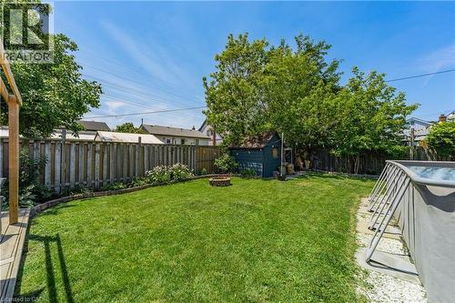Expansive backyard featuring a lush lawn, wood fencing, a dedicated fire pit area, an outdoor shed, and mature trees providing natural screening - 621 Tate Avenue, Hamilton, ON - Outdoor With Backyard