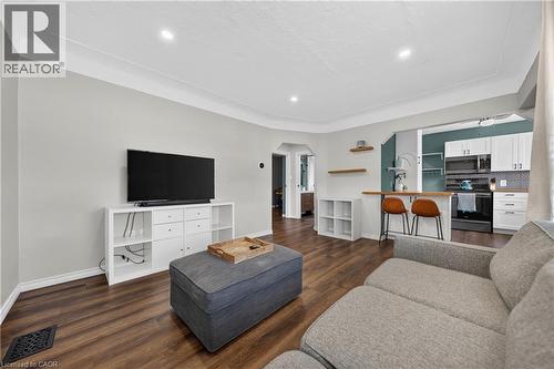 Open-concept living space featuring wood-finish flooring, recessed lighting, crown molding, a kitchen passthrough with a wood-finish bar top, and a tiled kitchen backsplash - 621 Tate Avenue, Hamilton, ON - Indoor Photo Showing Living Room