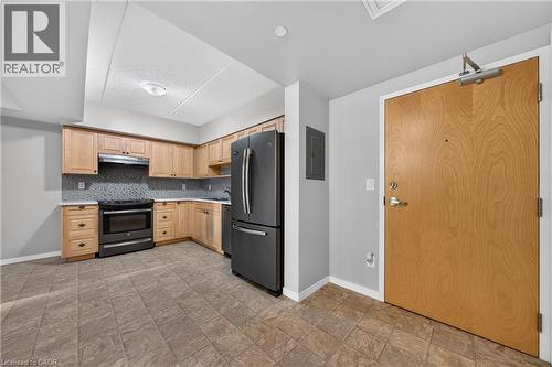 Kitchen featuring wood cabinetry, light countertops, a tile backsplash, and stainless steel appliances - 155 Water Street S Unit# 203, Cambridge, ON - Indoor Photo Showing Kitchen With Stainless Steel Kitchen