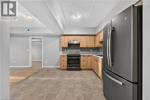 Kitchen featuring wood cabinetry, dark-finish appliances, and tiled flooring - 155 Water Street S Unit# 203, Cambridge, ON - Indoor Photo Showing Kitchen With Stainless Steel Kitchen