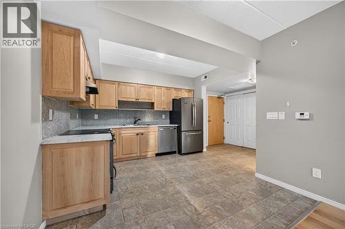 Kitchen featuring light wood cabinetry, stainless steel appliances, a tile backsplash, and light-toned countertops - 155 Water Street S Unit# 203, Cambridge, ON - Indoor Photo Showing Kitchen