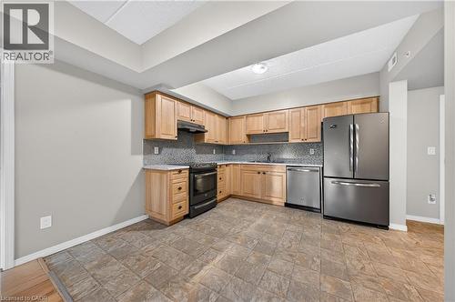 Kitchen featuring natural wood-finish cabinetry, tile flooring, and light-toned countertops - 155 Water Street S Unit# 203, Cambridge, ON - Indoor Photo Showing Kitchen With Stainless Steel Kitchen