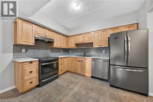 Functional kitchen featuring light wood cabinetry, a mosaic tile backsplash, solid surface countertops, stainless steel appliances, and tile flooring - 155 Water Street S Unit# 203, Cambridge, ON - Indoor Photo Showing Kitchen With Stainless Steel Kitchen