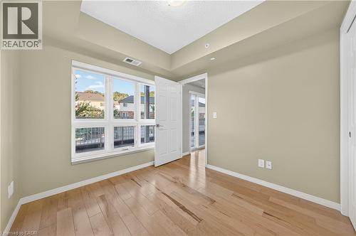 Room with wood-finish flooring, neutral wall paint, and a large multi-pane window - 155 Water Street S Unit# 203, Cambridge, ON - Indoor Photo Showing Other Room