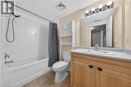 Full bathroom featuring a tub/shower combination with white subway tile surround, a natural wood-finish vanity with a light-toned countertop and integrated sink, and an overhead lighting fixture - 155 Water Street S Unit# 203, Cambridge, ON - Indoor Photo Showing Bathroom