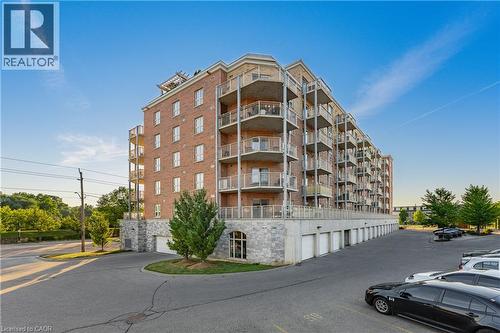 Multi-story residential building featuring a brick facade and stone-clad lower levels - 155 Water Street S Unit# 203, Cambridge, ON - Outdoor With Facade
