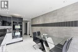 Modern kitchen and dining area featuring high-gloss black and white cabinetry, built-in double ovens, and recessed ceiling lighting - 
