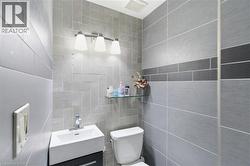Modern bathroom featuring a wall-mounted vanity with integrated sink, contemporary tiling, and a three-light vanity fixture - 