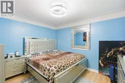 Bedroom featuring light blue walls with white trim and wood-finish flooring - 