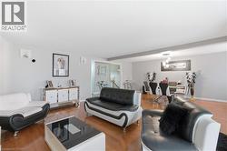 Open-concept living space featuring wood-finish flooring, light gray wall paint, and a dining area with a contemporary chandelier - 