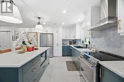 Open-concept kitchen with stone countertop island, two-tone cabinets and modern stainless steel appliances - 