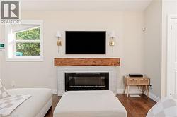 Living area featuring a modern fireplace with a white tile surround and a rustic wood mantel - 