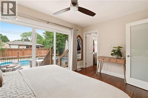 Sliding glass doors opening to an exterior deck with privacy fencing and an in-ground pool - 715 Drury Lane, Burlington, ON - Indoor Photo Showing Bedroom