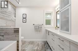 Modern bathroom featuring large format gray-toned tile flooring and a matching tiled shower surround - 