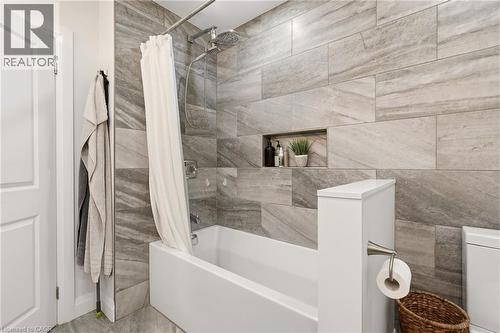 Bathroom featuring a tiled shower surround with a built-in niche, a shower-over-tub configuration, and a rain shower head - 715 Drury Lane, Burlington, ON - Indoor Photo Showing Bathroom
