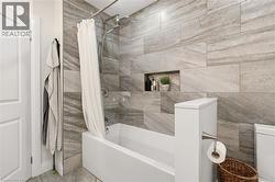 Bathroom featuring a tiled shower surround with a built-in niche, a shower-over-tub configuration, and a rain shower head - 