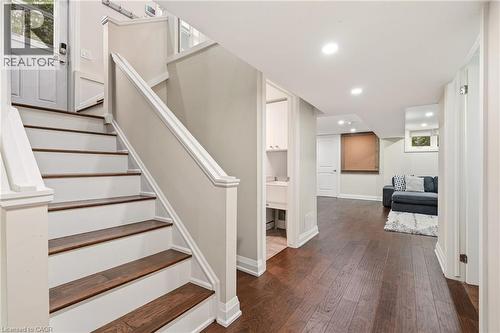 Staircase with wood-finish treads and painted risers, featuring a white handrail and newel posts - 715 Drury Lane, Burlington, ON - Indoor Photo Showing Other Room