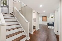 Staircase with wood-finish treads and painted risers, featuring a white handrail and newel posts - 