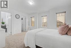 Carpeted bedroom featuring multiple windows, white walls, and an attached three-piece bathroom with a single vanity - 