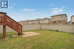 Expansive backyard featuring a wood deck with stairs, a concrete patio, and a perimeter fence - 