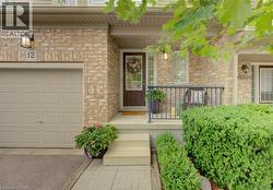 Brick exterior featuring an integrated garage, a covered porch with a metal railing, and a paved walkway - 