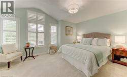 Vaulted ceiling bedroom with light-toned wall paint and plush carpeting - 