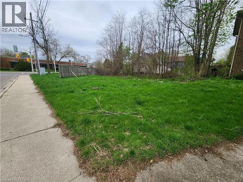 Expansive grass lot featuring mature perimeter trees and a sidewalk border - 685 Brant Street, Burlington, ON 