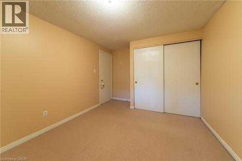Room featuring tan walls, light brown carpeting, white baseboards, and a textured ceiling - 426 Downsview Place, Waterloo, ON - Indoor Photo Showing Other Room