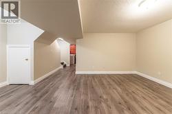 Spacious room with wood-finish flooring, light beige walls, white baseboards, and overhead lighting - 