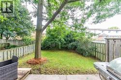 Landscaped backyard featuring a mature tree, manicured lawn, and wooden privacy fencing - 