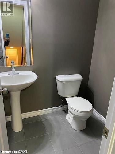 Powder room featuring a pedestal sink with a chrome faucet, a white toilet, gray wall color, and gray tiled flooring - 4 Isaiah Drive, Kitchener, ON - Indoor Photo Showing Bathroom