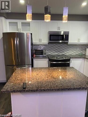 Kitchen island with a polished stone countertop and pendant lighting - 4 Isaiah Drive, Kitchener, ON - Indoor Photo Showing Kitchen With Stainless Steel Kitchen With Upgraded Kitchen