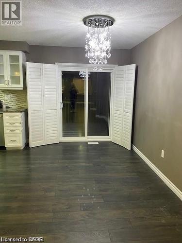 Sliding glass doors featuring white louvered shutters, accompanied by a crystal-style chandelier - 4 Isaiah Drive, Kitchener, ON - Indoor Photo Showing Other Room