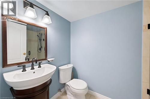 Bathroom featuring a pedestal-style sink with a dark wood-finish vanity base, oil-rubbed bronze fixtures, a framed mirror, and a three-light vanity bar - 688 Preston Parkway Unit# 401, Cambridge, ON - Indoor Photo Showing Bathroom