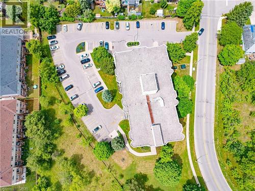 Building exterior with light gray roofing, surrounded by extensive asphalt parking areas, mature trees, and landscaping - 688 Preston Parkway Unit# 401, Cambridge, ON - Outdoor With View