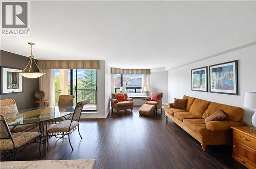 Spacious living area featuring dark wood-finish flooring, a contemporary ceiling light fixture, and floor-to-ceiling windows with a balcony access - 688 Preston Parkway Unit# 401, Cambridge, ON - Indoor Photo Showing Living Room